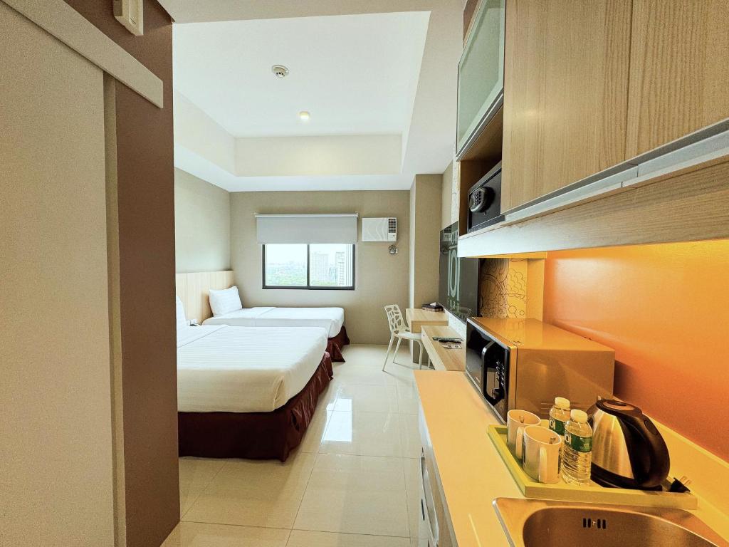 マニラにあるHotel101 - Fortのベッドとキッチン付きの小さなホテルルームです。