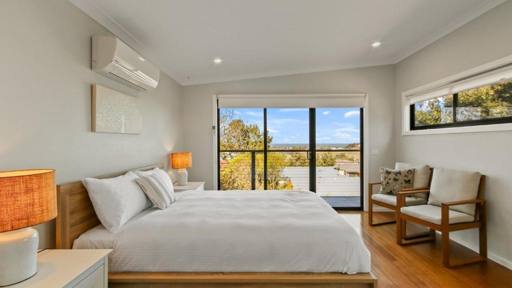 Un dormitorio con una cama grande y una ventana. en Anchored on Capes Upstairs, en Lakes Entrance