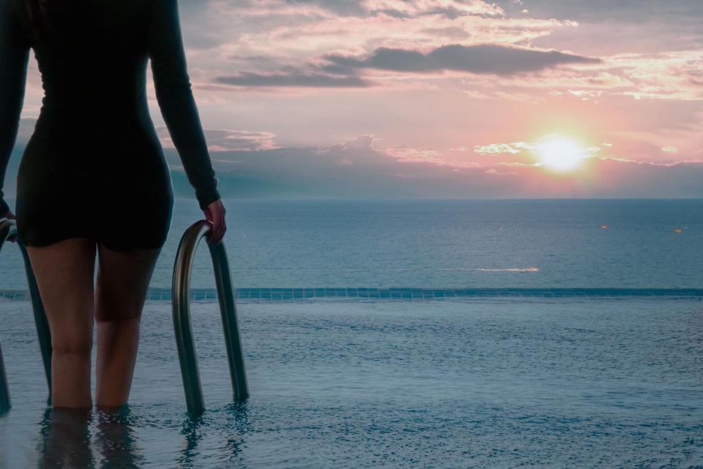 a woman standing in the water near the ocean at Awaken Da Nang Hotel in Danang