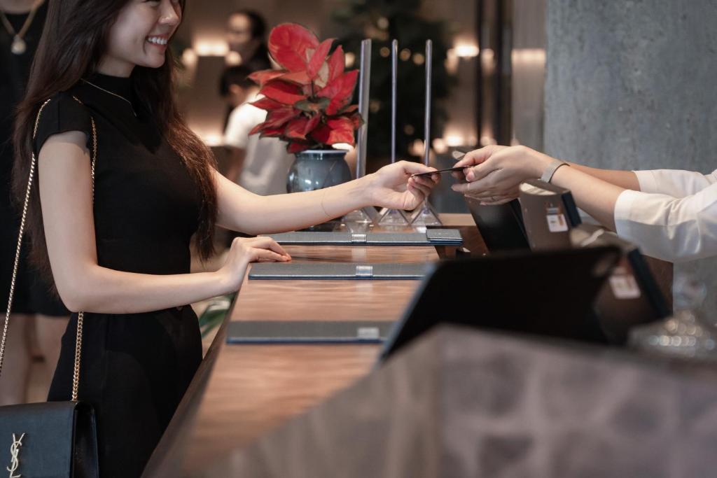 A guest checks in at a dark, wood-fronted hotel reception desk.