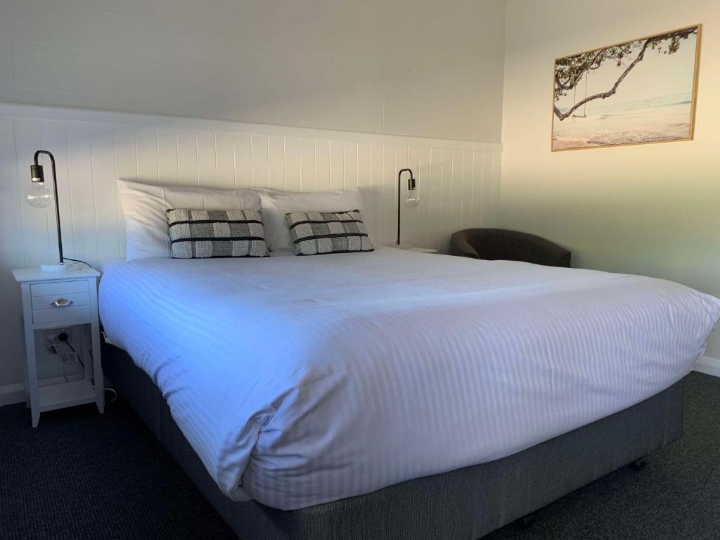 a bedroom with a large white bed with two pillows at Mudgee Vineyard Motor Inn in Mudgee