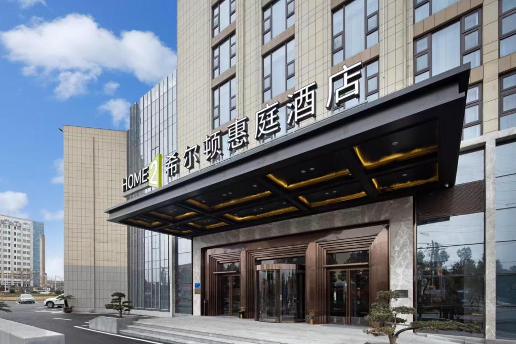 a building with a sign on top of it at Home2 Suites By Hilton Wuxi Huishan in Wuxi