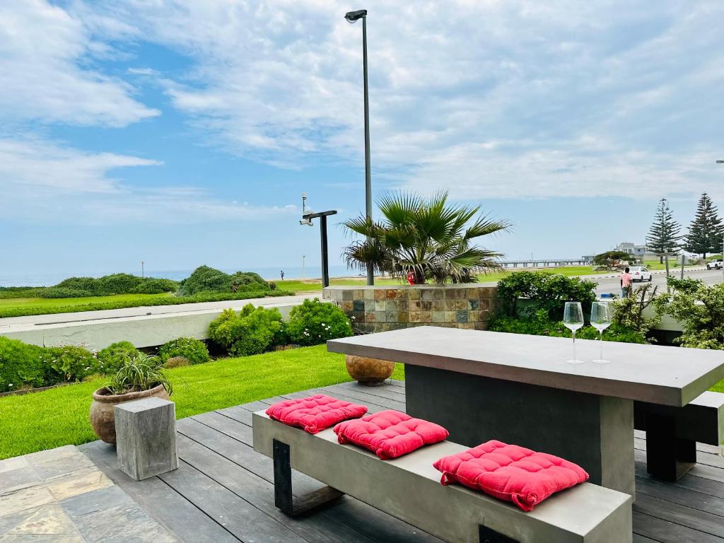 Una mesa y bancos con cojines rojos en un patio. en Atlantik Sicht Unit 1, en Swakopmund