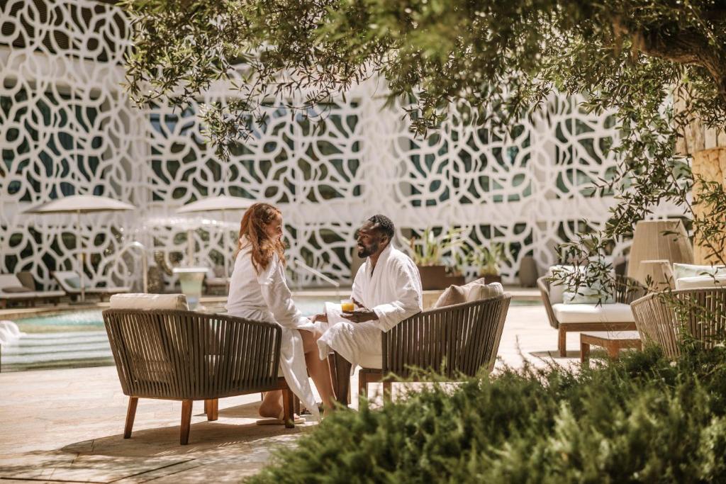 a man and woman sitting on chairs in a garden at Hard Rock Hotel Ibiza in Playa d'en Bossa