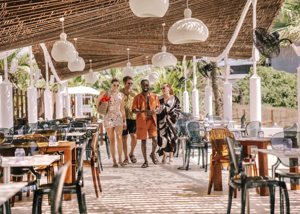 three people walking through a restaurant with tables and chairs at Hard Rock Hotel Ibiza in Playa d'en Bossa