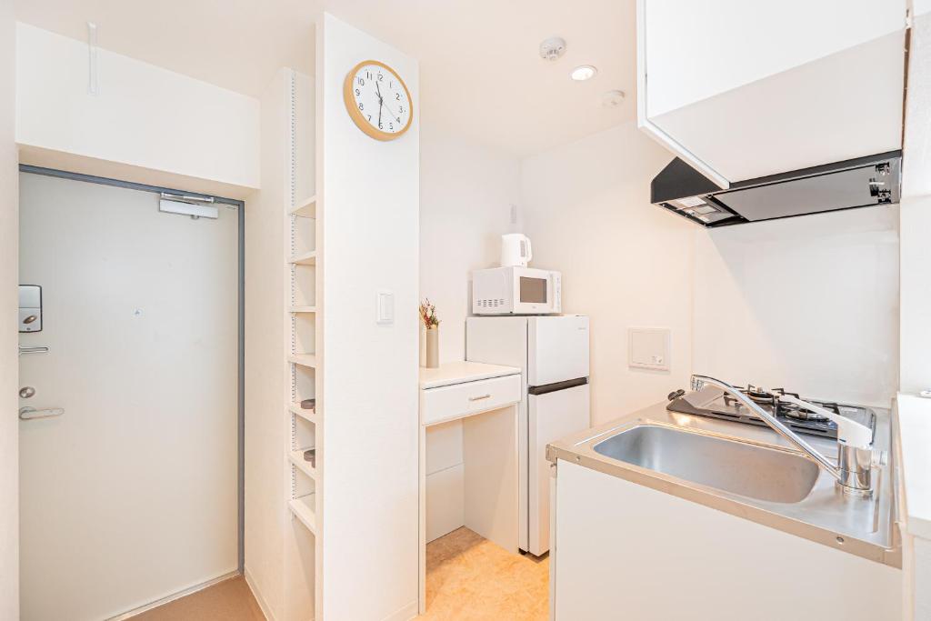 東京にあるNew Cozy APT Located on the Japanese Local shopping streetのシンクと壁に時計が付いたキッチン