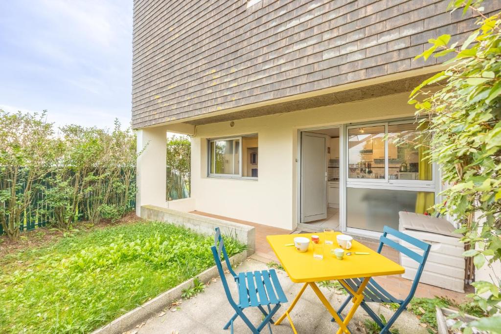 une table et des chaises jaunes devant une maison dans l'établissement Le Petit Cocon Marin - Appt à 200m de la plage, à Courseulles-sur-Mer