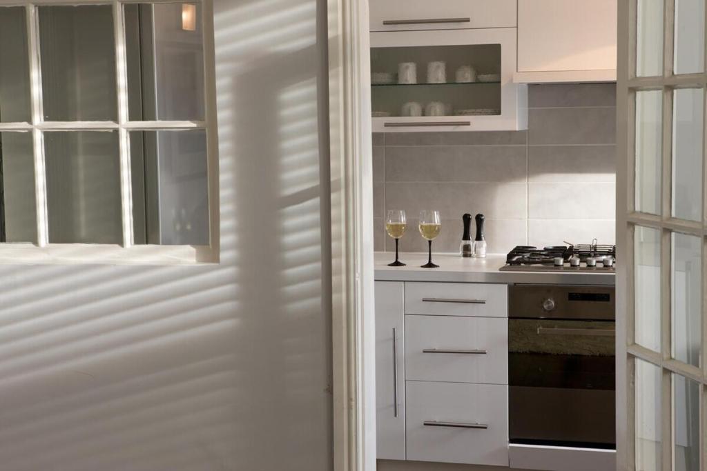 a kitchen with white cabinets and two glasses of wine at Warwick Place - Leamington Apartments in Leamington Spa