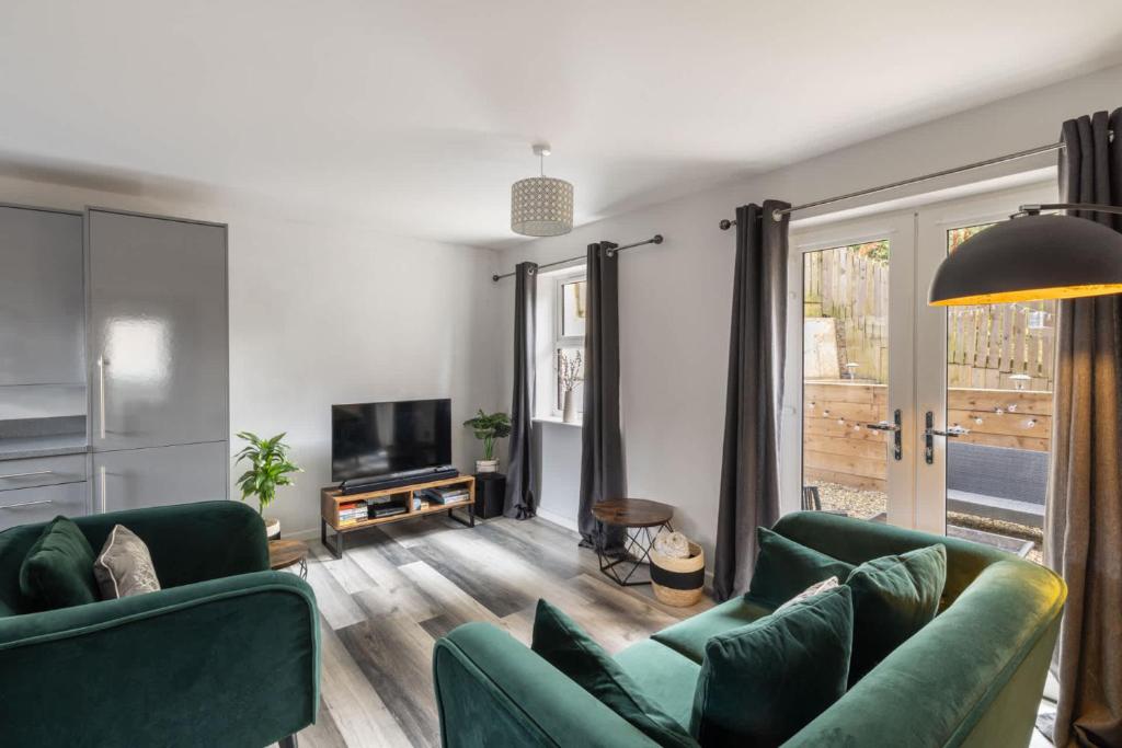 a living room with two green couches and a television at Host & Stay - Shipwright Lodge in Whitby