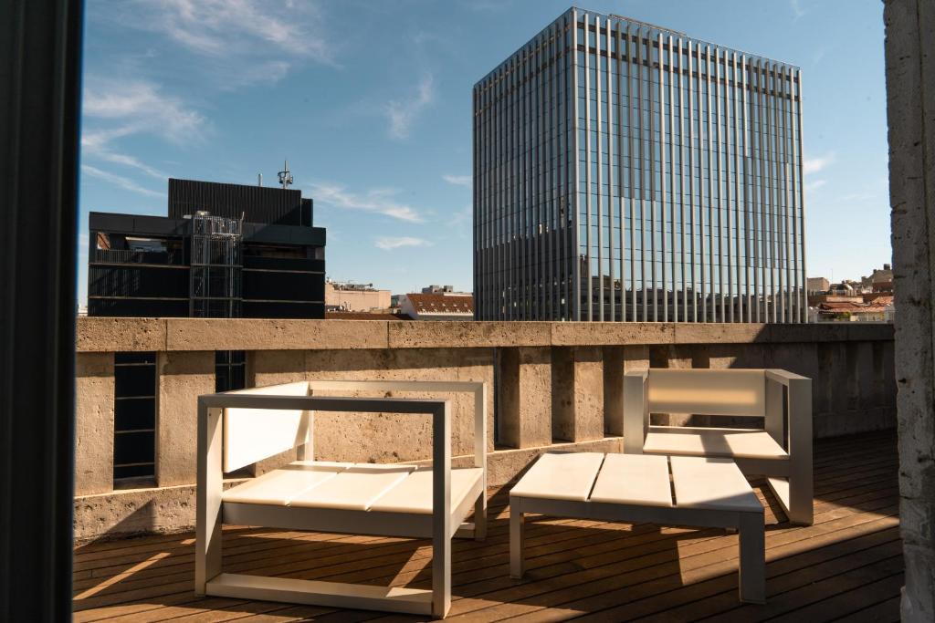 two white chairs on a balcony with a building at Petit Palace President Castellana in Madrid