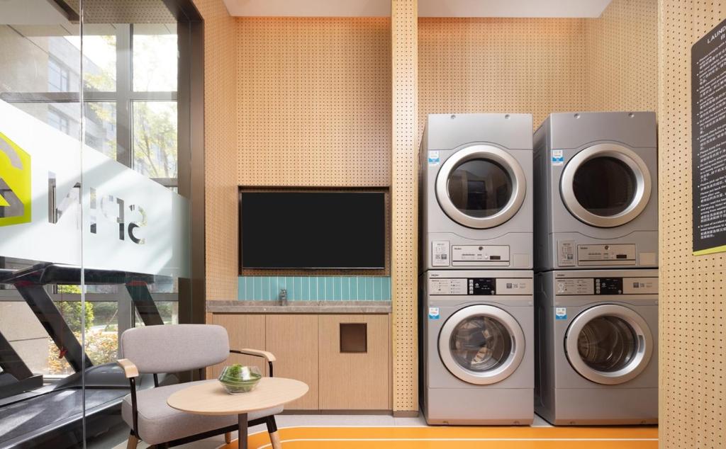 two washing machines and a tv in a room at Home2 by Suite Liaocheng Dongchang in Liaocheng