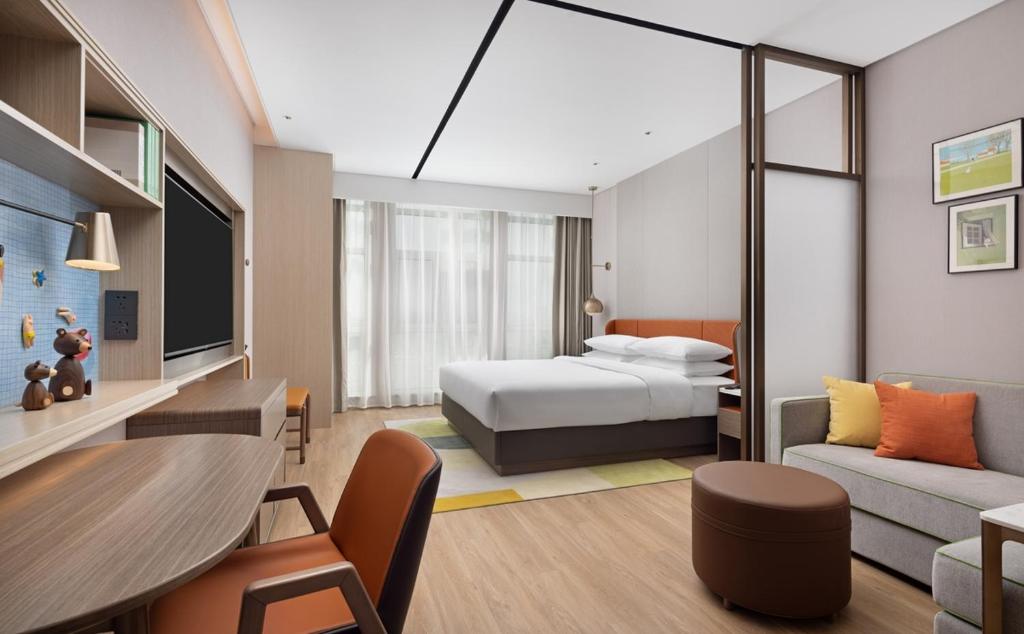 a hotel room with a bed and a couch at Home2 by Suite Liaocheng Dongchang in Liaocheng