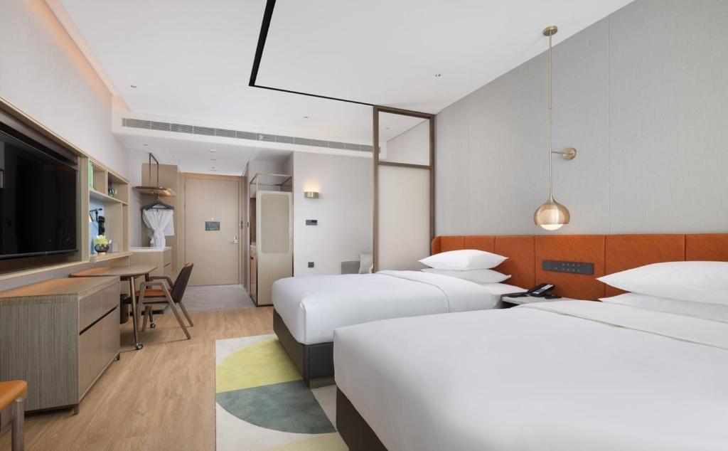 a hotel room with two beds and a flat screen tv at Home2 by Suite Liaocheng Dongchang in Liaocheng