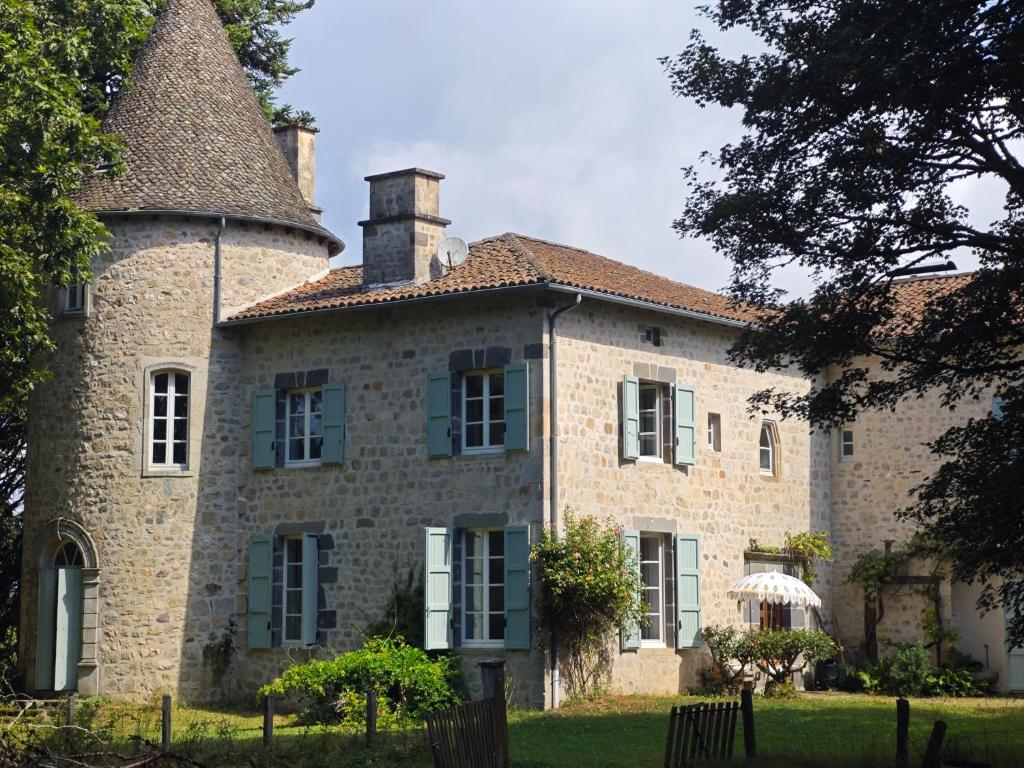 une ancienne maison en pierre avec une cheminée en haut dans l'établissement Manoir de famille proche lac, à Saint-Étienne-Cantalès