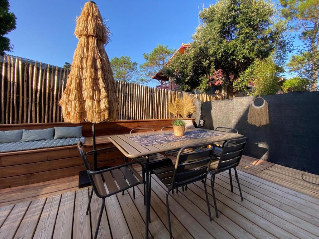 une terrasse en bois avec une table et des chaises. dans l'établissement Villa Cano Beach, à Lacanau-Océan
