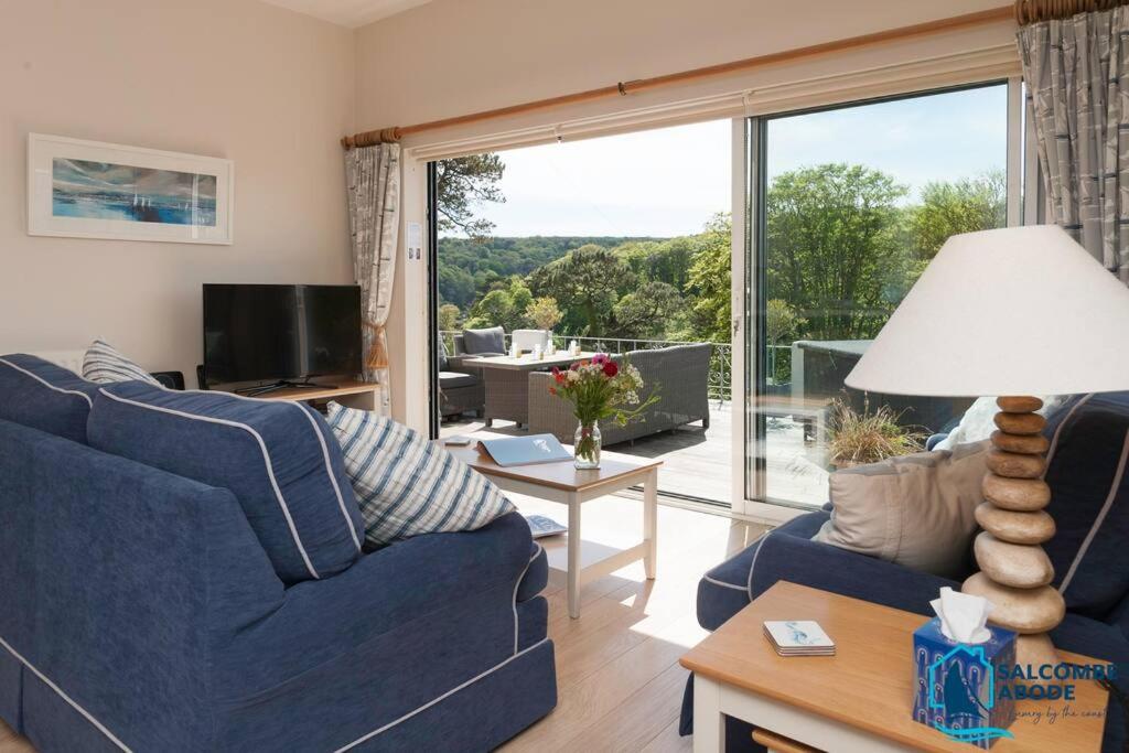 ein Wohnzimmer mit einer blauen Couch und einem großen Fenster in der Unterkunft Elevated Coastal Escape - Breathtaking Views in Salcombe