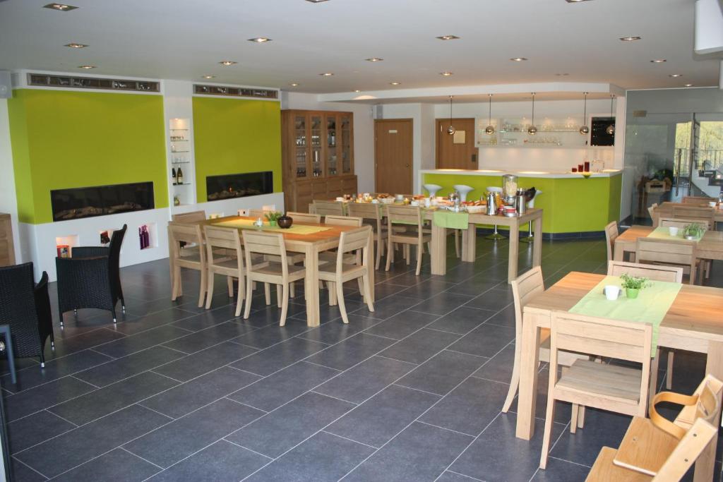 a restaurant with wooden tables and chairs and green walls at Hotel Gasthof Kapelhof in Erpe-Mere