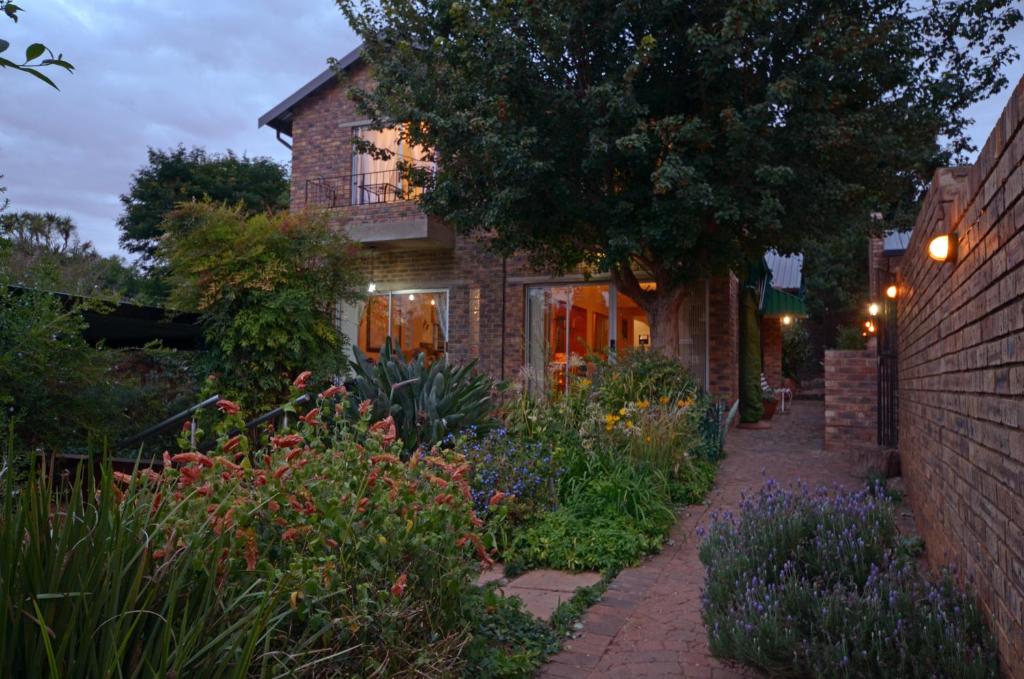 a garden in front of a brick house with flowers at B&B on 8th Avenue in Johannesburg