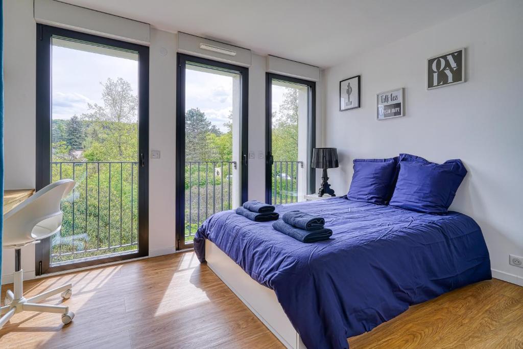 Cette chambre comprend un lit avec des draps bleus et un balcon. dans l'établissement Chambre cosy - cadre verdoyant - Proche saclay, à Gif-sur-Yvette