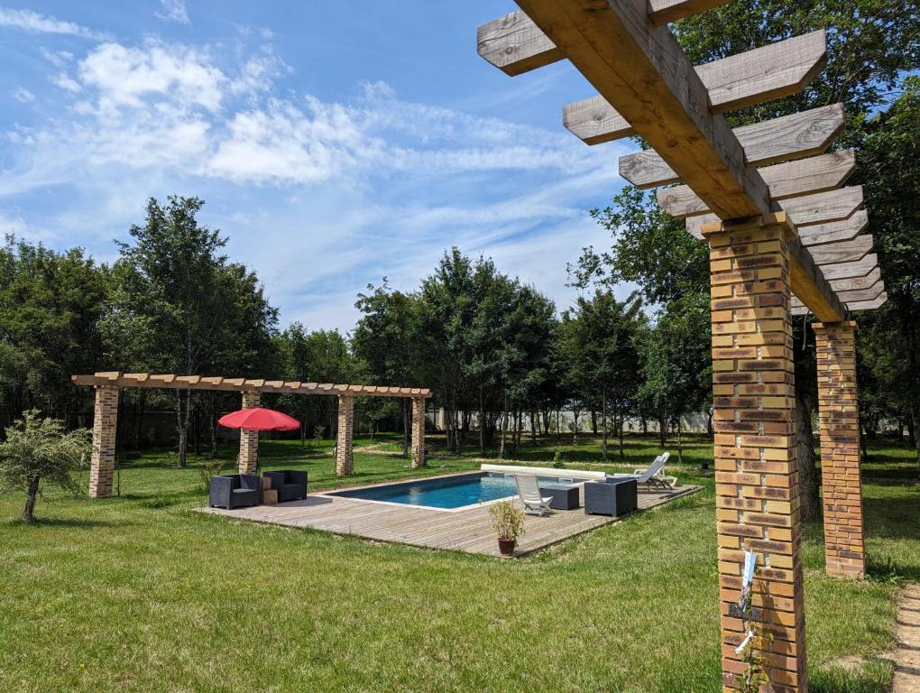 einen Hinterhof mit einem Pool und einer Pergola in der Unterkunft L' Évasion en plein air in Fontenay-sur-Loing