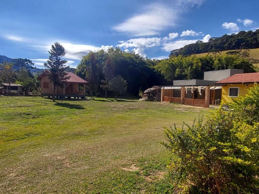 a large yard with a house and a building at Chalé Rústico Moderno no Cantagalo in São Bento do Sapucaí