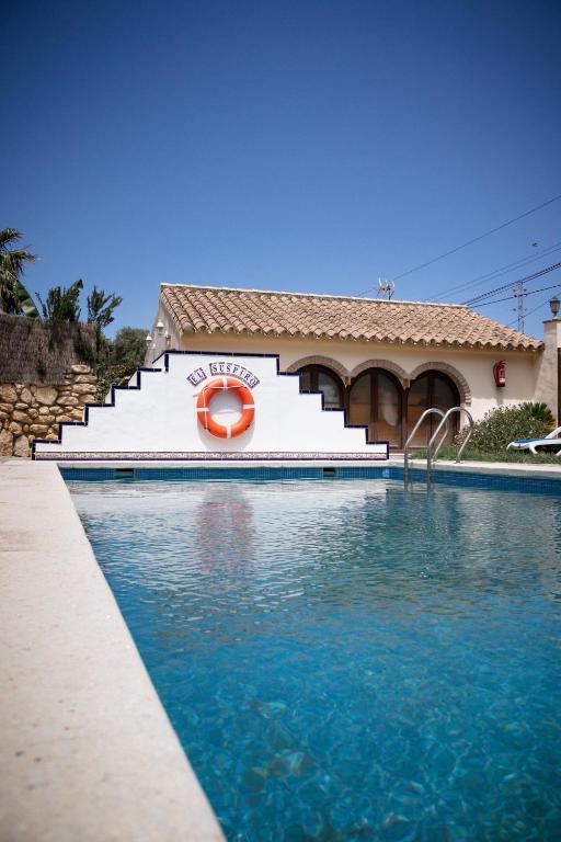 a swimming pool in front of a building with an orange life preserver at Casas El Suspiro in Zahora