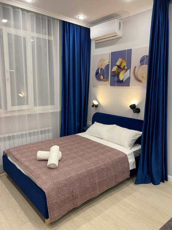 a bedroom with a large bed with blue curtains at Contento Apartments in Almaty
