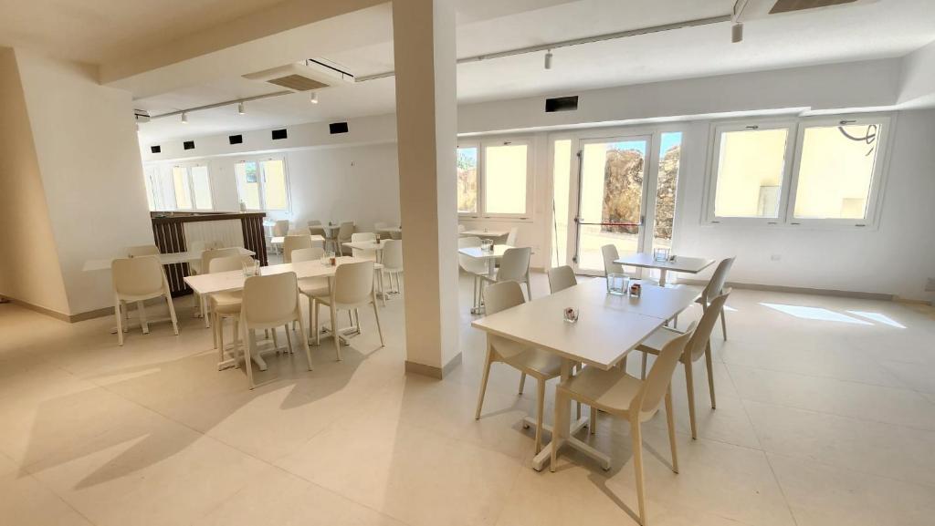 a dining room with tables and chairs and windows at Hotel Borgo Dell'Orso in Palau