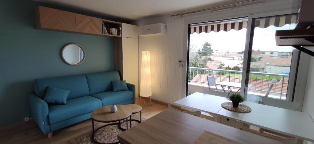 un salon avec un canapé bleu et une grande fenêtre dans l'établissement Studio Arcachon, quartier de l'Aiguillon, à Arcachon