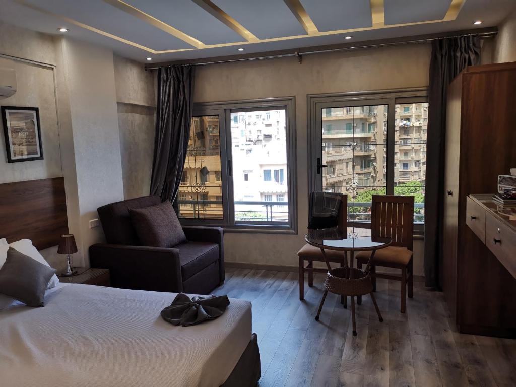 カイロにあるswiss hotel downtownのベッド、テーブル、椅子が備わるホテルルームです。