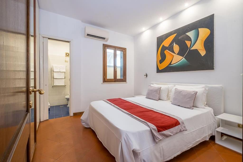 Un dormitorio con una cama blanca con un cuadro en la pared. en ht vicolo 6 bilo, en Roma