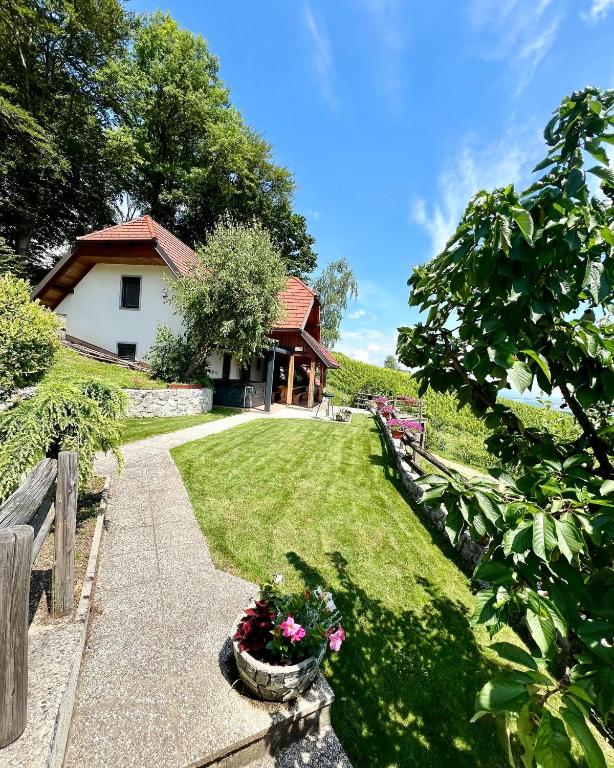 a garden with a house and a yard with flowers at Vineyard cottage Skriti raj in Leskovec pri Krškem