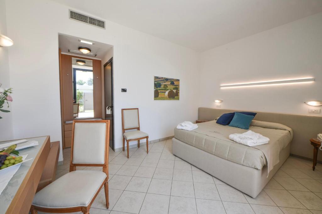 a bedroom with a bed and a table and chairs at Grand Hotel Masseria Santa Lucia in Ostuni