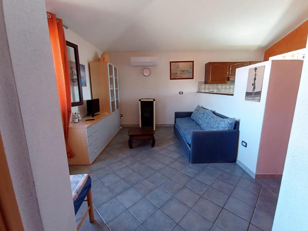 salon z niebieską kanapą i kuchnią w obiekcie Appartamento Sardegna - accogliente e luminoso w mieście Porto San Paolo