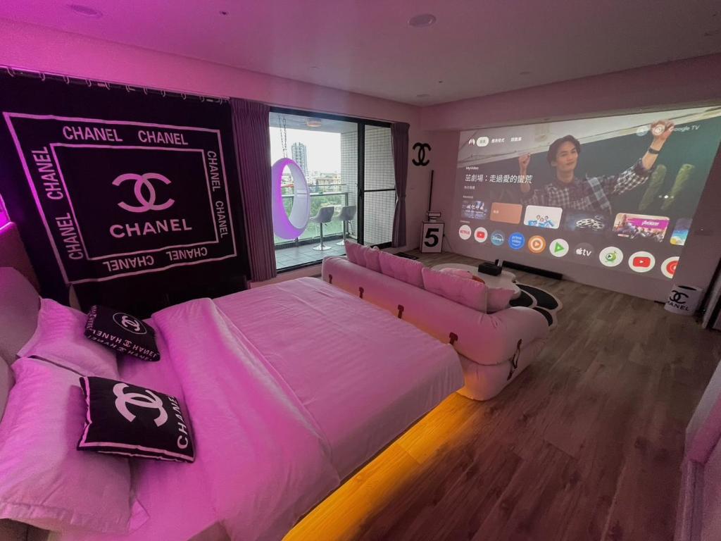 a room with a pink bed and a large screen at 光嶼海溫泉海景無邊際泳池豪華套房 in Hsin-hsing