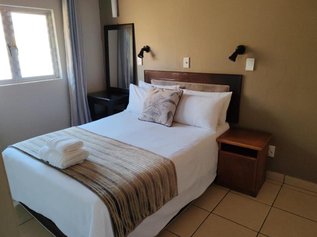 a bedroom with a large bed with white sheets and pillows at Chakas Rock Chalets - Unit 19 in Ballito