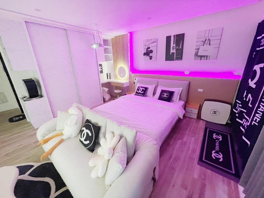 a bedroom with a bed and a couch and pink lights at 光嶼海溫泉海景無邊際泳池豪華套房 in Hsin-hsing