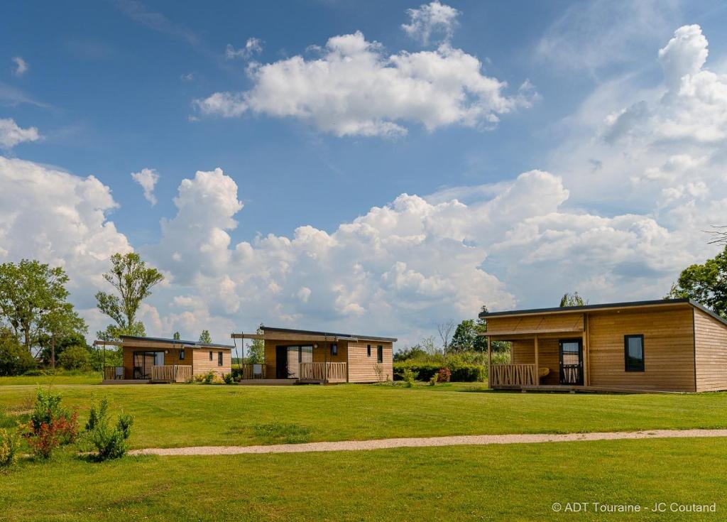 two houses on a grassy field with clouds in the sky at Cottages du Golf Fleuray-Amboise in Cangey