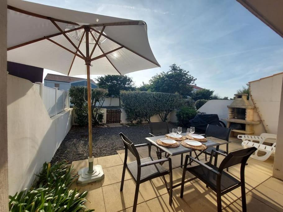 a table and chairs with an umbrella on a patio at Le Hameau du Phare - La Chaume 100 m plage in La Chaume