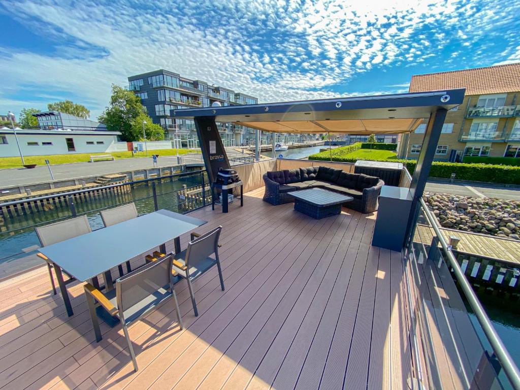 a deck with a table and chairs and a couch at MarinaVilla in Nykøbing Falster