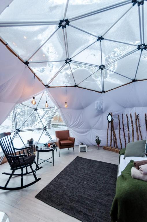a room with a tent with a couch and a chair at GLØD Aurora Canvas Dome in Alta