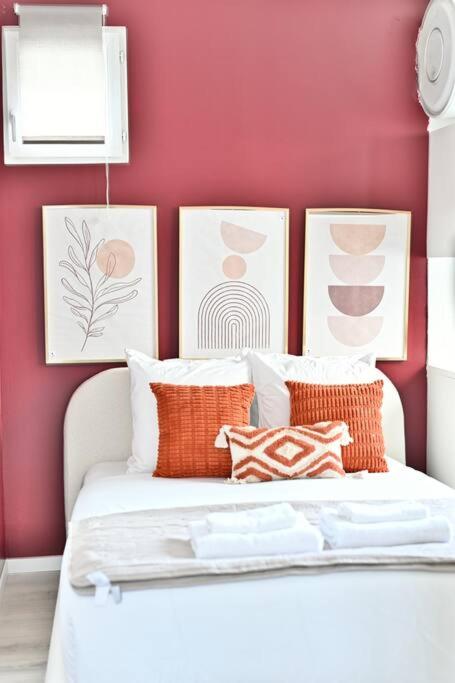 - une chambre avec des murs rouges et un lit avec des oreillers dans l'établissement Studio Cosy près de Montparnasse - II, à Paris