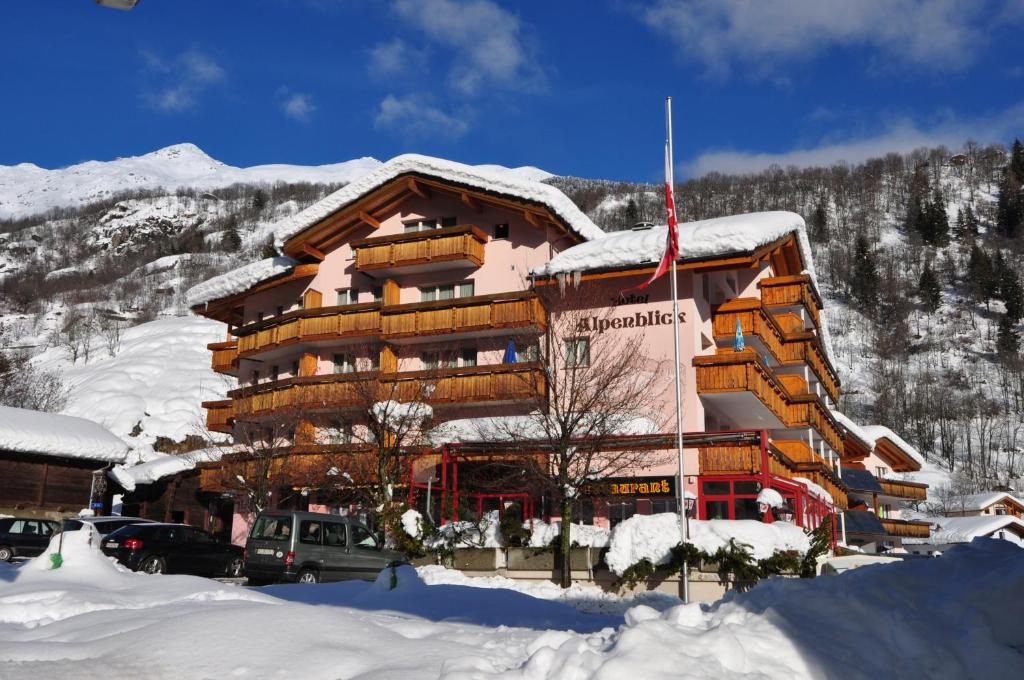 een groot houten gebouw met sneeuw op de grond bij Aktiv- und Genusshotel Alpenblick in Fiesch