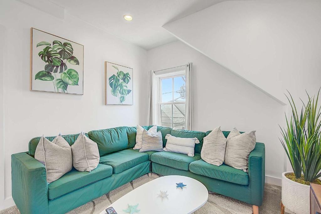 Una sala de estar con un sofá azul y una mesa. en Oasis on Commercial Street w Balcony, en Provincetown