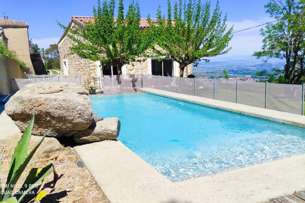 une grande piscine avec un rocher à côté d'une maison dans l'établissement Villa spacieuse -Vue exceptionnelle- Piscine, à Saint-Romain-de-Lerps