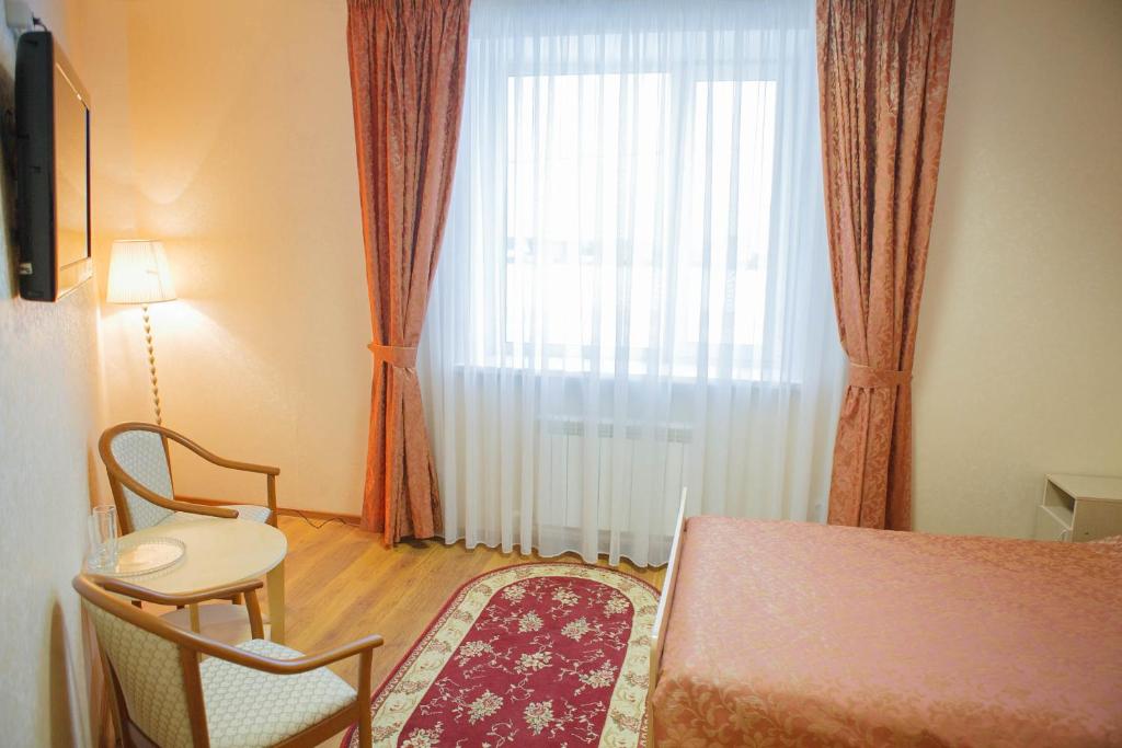 um quarto com uma cama, uma janela e uma cadeira em Oskar em Pereslavl-Zalessky