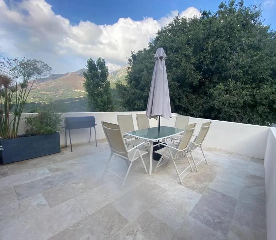 un patio avec une table, des chaises et un parasol dans l'établissement Appartement charmant à Feliceto 80 m² avec terrasse, à Feliceto