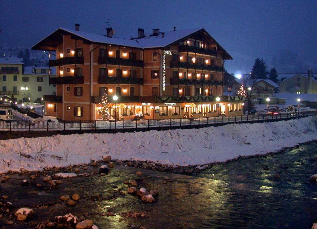 a large building with christmas lights in front of a river at Albergo Conca Verde in Fiera di Primiero