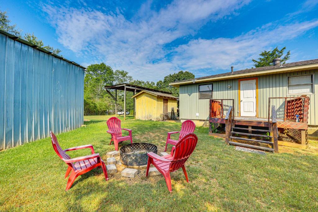 a group of red chairs sitting around a fire pit at Rural Escape Near Lake Ouachita with Gas Grill! in Pearcy