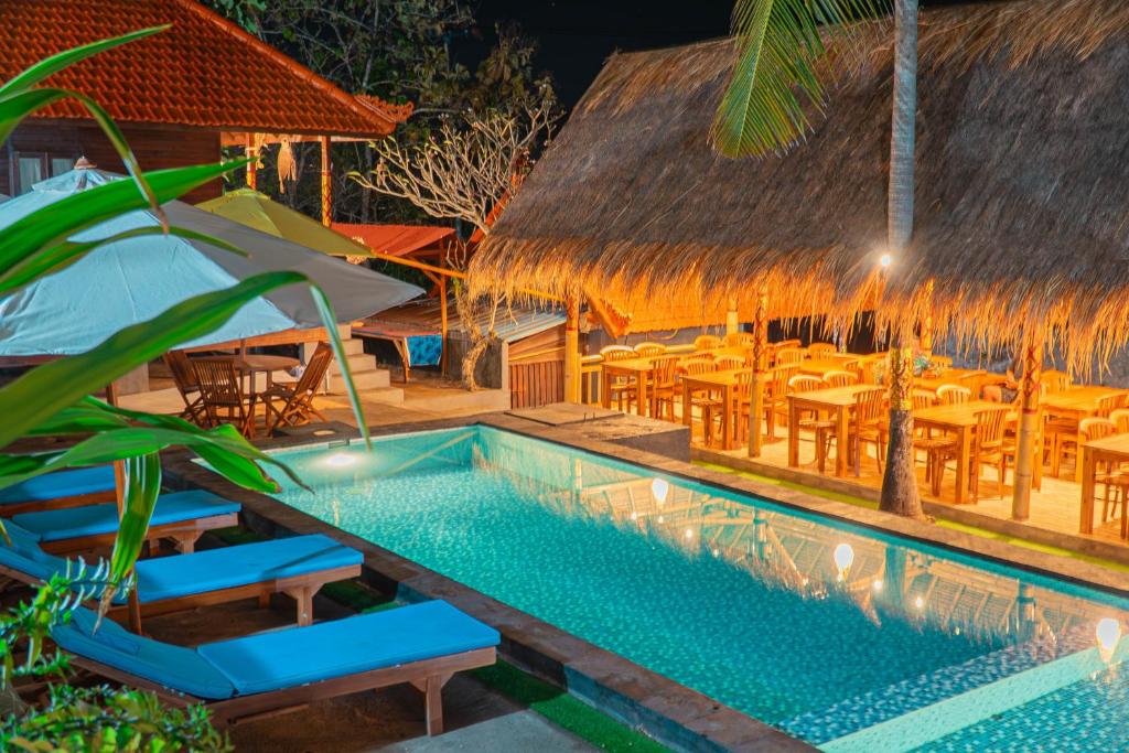 a resort pool with tables and chairs at night at The Aura Penida Hills By Bali Cabin in Nusa Penida
